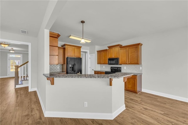kitchen with a breakfast bar area, decorative backsplash, and black appliances