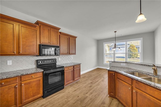 kitchen featuring sink, hanging light fixtures, light hardwood / wood-style flooring, a notable chandelier, and black appliances