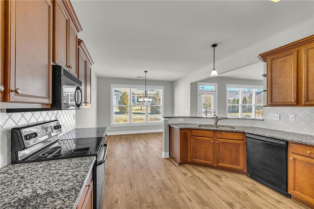 kitchen with stone counters, sink, a notable chandelier, decorative backsplash, and black appliances