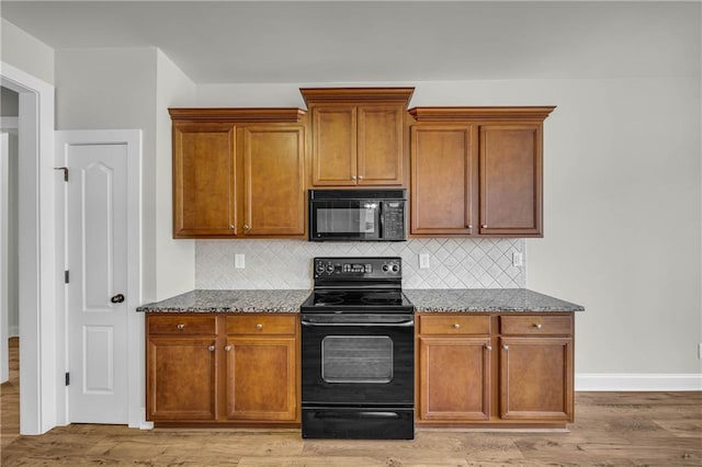 kitchen with dark stone countertops, decorative backsplash, light hardwood / wood-style flooring, and black appliances