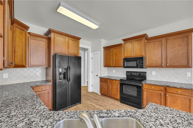 kitchen with decorative backsplash, light wood-type flooring, sink, and black appliances