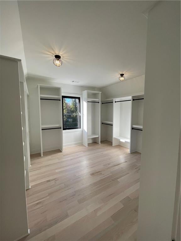 unfurnished bedroom with a barn door and light hardwood / wood-style floors