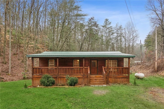 view of front of home with a front yard, log veneer siding, and metal roof