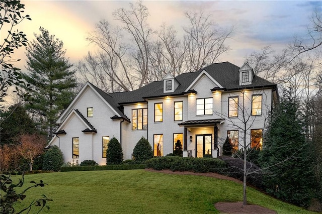 view of front facade with brick siding and a yard