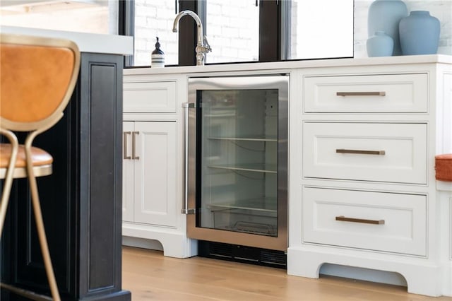 bar with light wood finished floors, wine cooler, and a sink