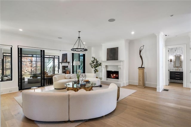 living area with recessed lighting, a warm lit fireplace, light wood-style flooring, and baseboards