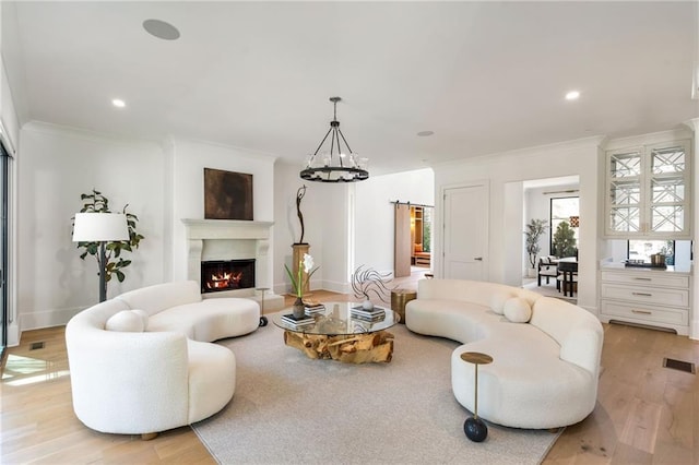 living room featuring ornamental molding, a lit fireplace, visible vents, and light wood-style flooring