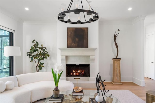 living area featuring a lit fireplace, ornamental molding, wood finished floors, and recessed lighting