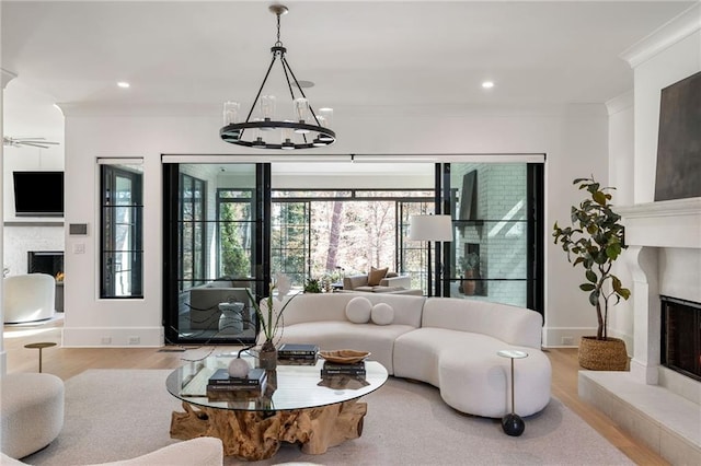 living area with a fireplace with raised hearth, crown molding, and wood finished floors