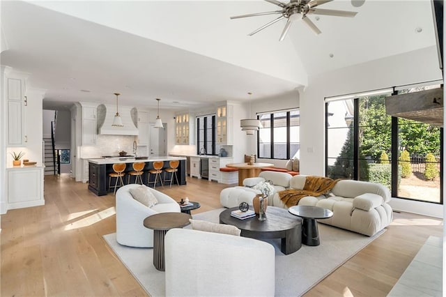 living area with vaulted ceiling, ceiling fan, beverage cooler, and light wood-style flooring