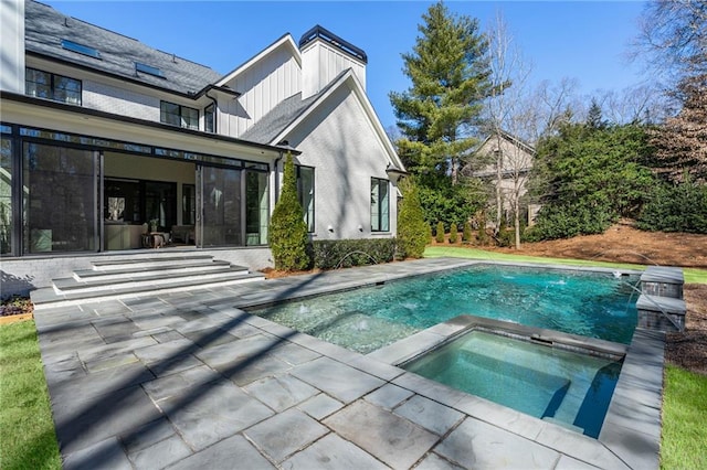 back of house featuring brick siding, a patio, board and batten siding, an in ground hot tub, and an outdoor pool