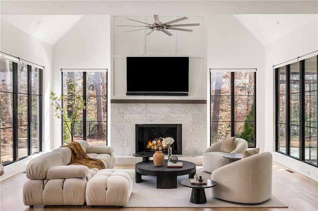 living room with a warm lit fireplace, high vaulted ceiling, wood finished floors, and visible vents