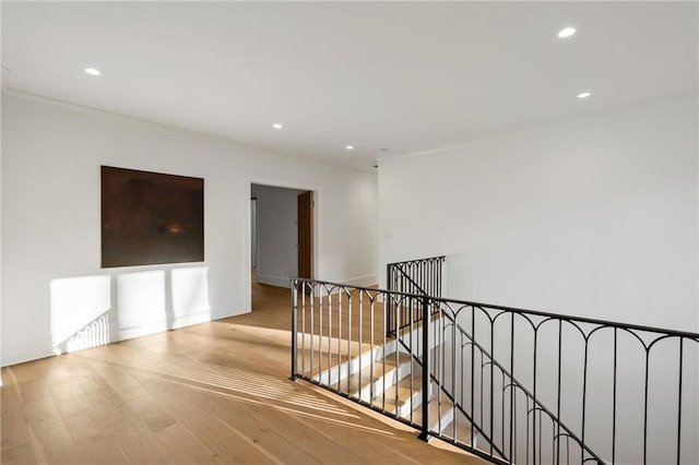 corridor with crown molding, wood finished floors, an upstairs landing, and recessed lighting