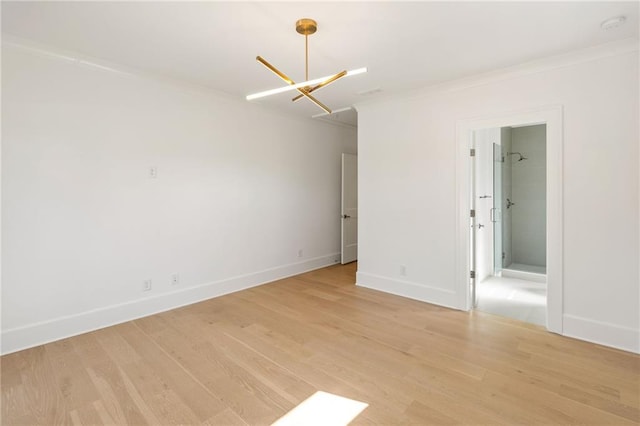 spare room featuring light wood-style floors, baseboards, ornamental molding, and a notable chandelier