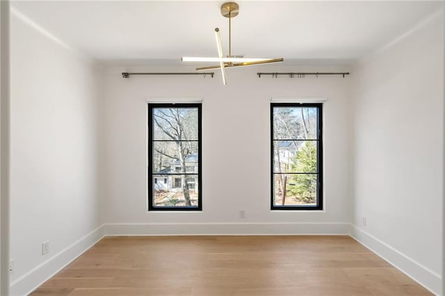 spare room featuring light wood-type flooring and baseboards