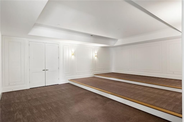 interior space with dark colored carpet and a decorative wall