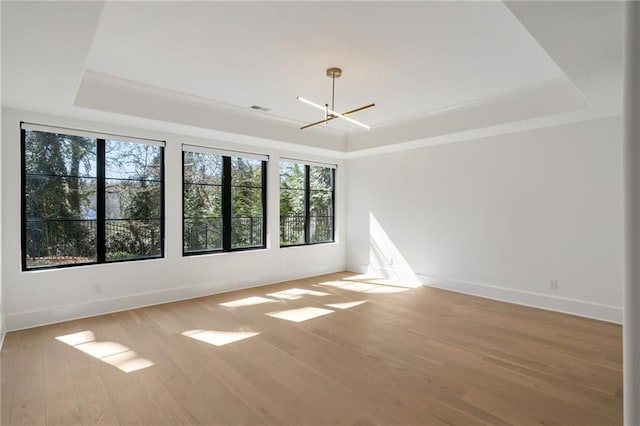 unfurnished room featuring light wood-type flooring, visible vents, and a tray ceiling