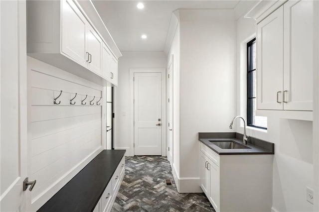 mudroom with baseboards, brick floor, a sink, and recessed lighting