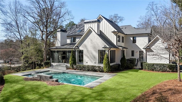 back of house featuring a lawn, an outdoor pool, board and batten siding, and brick siding