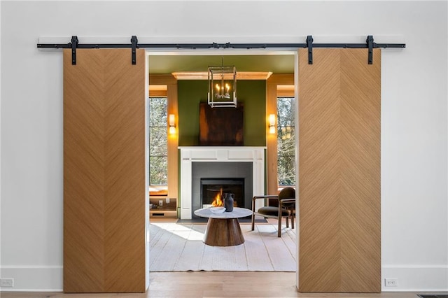 living area with a barn door, a wealth of natural light, and wood finished floors