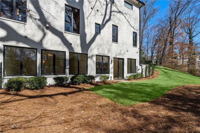 rear view of property featuring a yard and brick siding