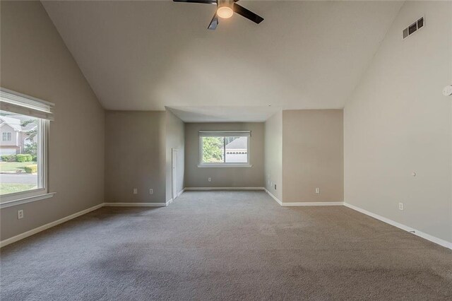 carpeted empty room with ceiling fan, visible vents, baseboards, and lofted ceiling