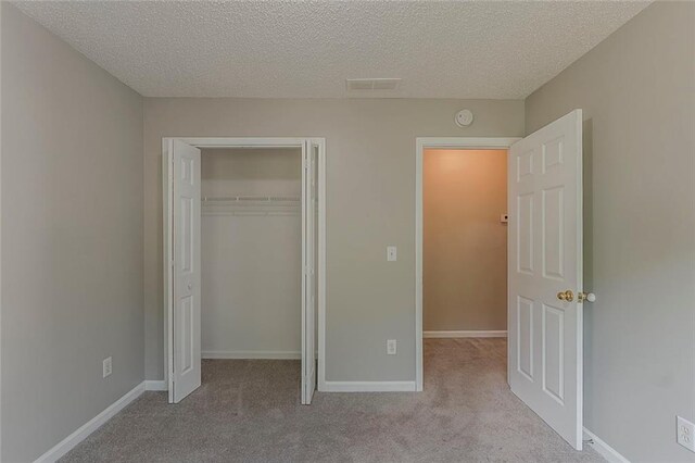 unfurnished bedroom featuring carpet flooring, a textured ceiling, and baseboards