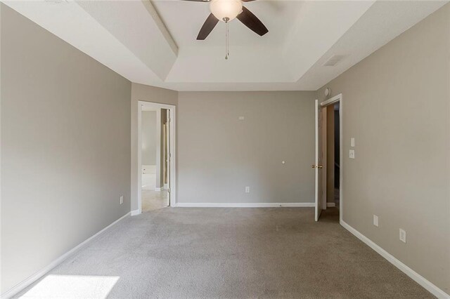 unfurnished room featuring ceiling fan, visible vents, a raised ceiling, baseboards, and carpet floors