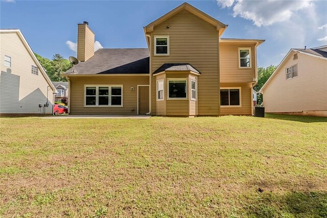 back of property featuring a lawn, a patio, a chimney, and cooling unit