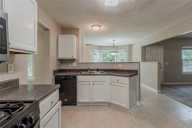 kitchen with a sink, a peninsula, dishwasher, and dark countertops