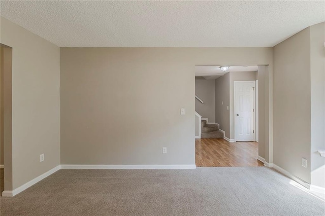 carpeted spare room featuring baseboards, stairs, and a textured ceiling