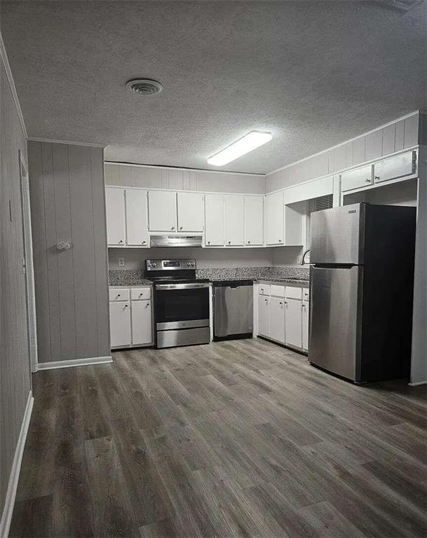 kitchen with appliances with stainless steel finishes, a textured ceiling, dark hardwood / wood-style floors, and white cabinets