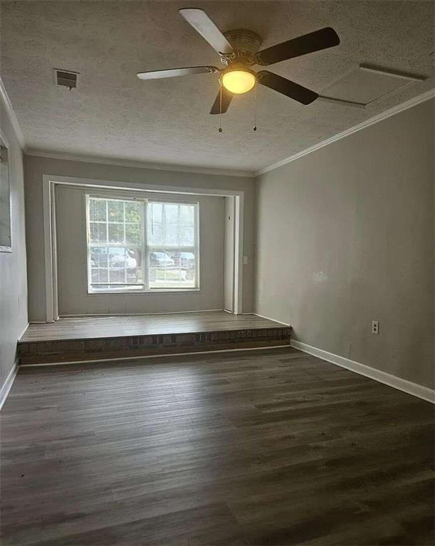 spare room featuring ceiling fan, ornamental molding, a textured ceiling, and dark hardwood / wood-style flooring