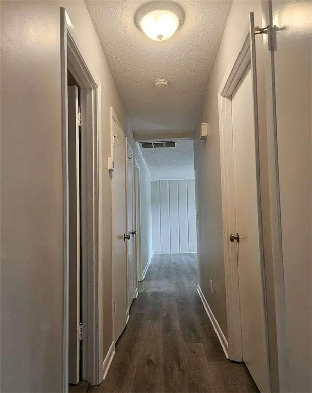 corridor with a textured ceiling and dark hardwood / wood-style flooring