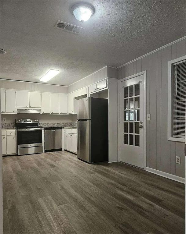 kitchen featuring a textured ceiling, stainless steel appliances, dark hardwood / wood-style flooring, and white cabinetry