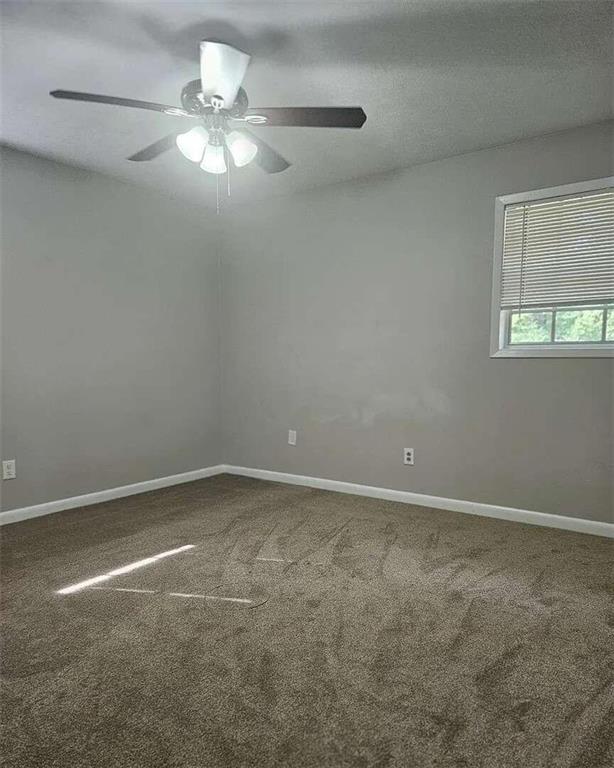 carpeted spare room featuring a textured ceiling and ceiling fan