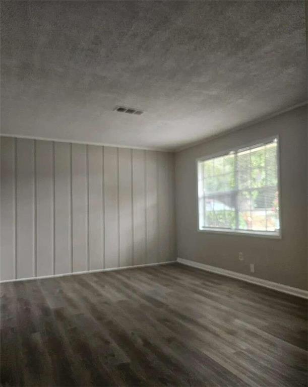 spare room featuring a textured ceiling and dark wood-type flooring