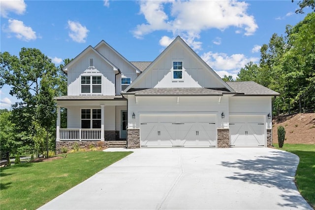 view of front of property featuring concrete driveway, stone siding, a porch, board and batten siding, and a front yard