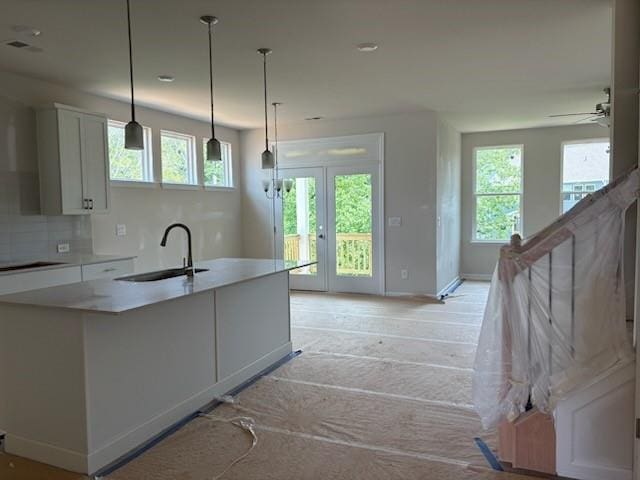 385 Riverwood Pass, Dallas, GA 30157 - kitchen with white cabinetry, tasteful backsplash, light countertops, hanging light fixtures, and an island with sink