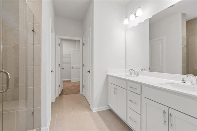 full bathroom with double vanity, tile patterned flooring, a shower stall, and a sink