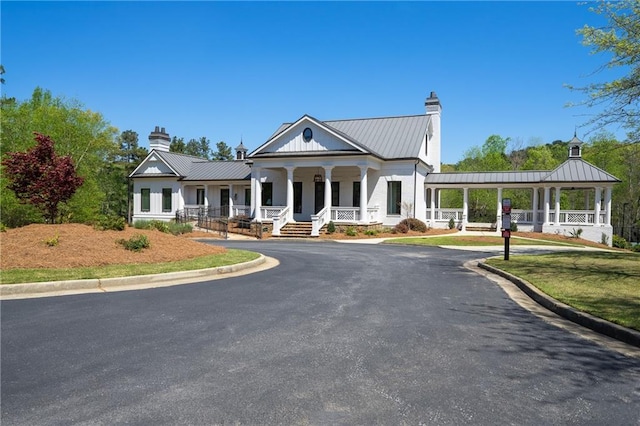 greek revival inspired property with a standing seam roof, a chimney, and metal roof