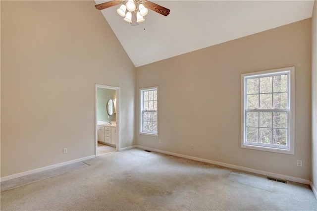 unfurnished room with ceiling fan, a healthy amount of sunlight, light colored carpet, and high vaulted ceiling