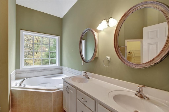 bathroom with tiled bath, vanity, and lofted ceiling