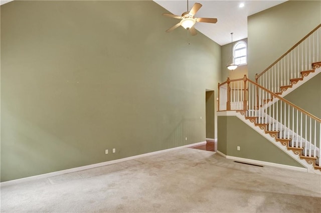 carpeted spare room featuring ceiling fan and high vaulted ceiling