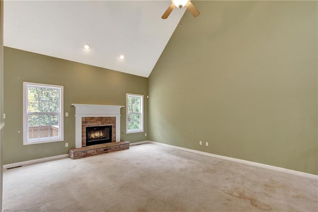 unfurnished living room featuring ceiling fan, a stone fireplace, carpet floors, and high vaulted ceiling