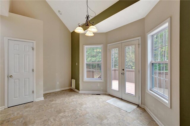 entryway featuring vaulted ceiling, plenty of natural light, french doors, and an inviting chandelier