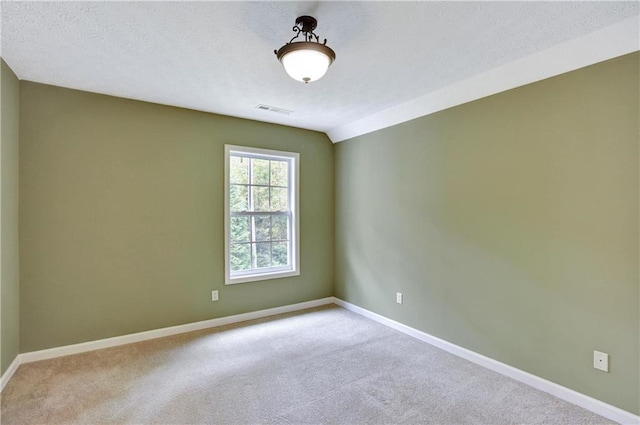 spare room with light carpet, a textured ceiling, and lofted ceiling