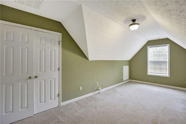 additional living space featuring light colored carpet, lofted ceiling, and a textured ceiling