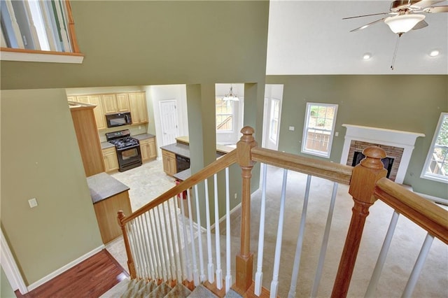 staircase with hardwood / wood-style flooring, ceiling fan with notable chandelier, and high vaulted ceiling