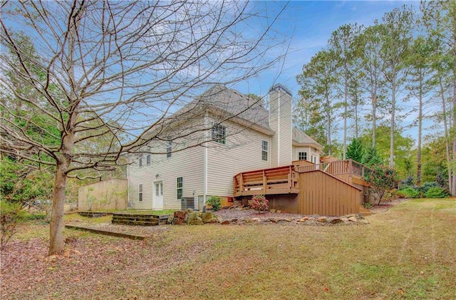 back of property featuring a wooden deck and a yard